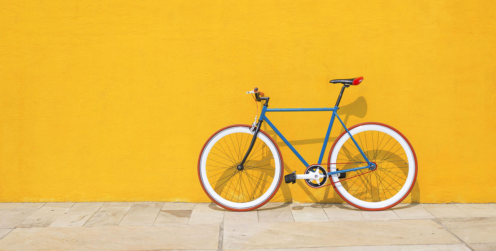 Un vélo accoté à un mur de briques.
